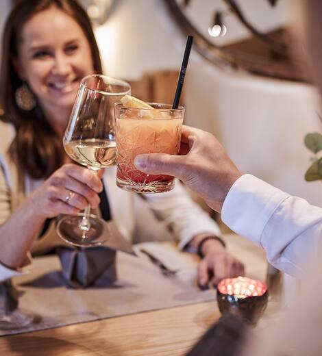 Paar stößt am Tisch mit Getränken an