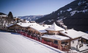 Aussenansicht des Hotel Astrid im Winter mit der Skipiste, die direkt am Hotel entlang führt 